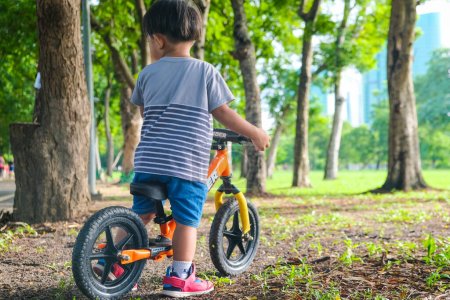 Foto de Preescolar asiático chico práctica equitación balansc bicicleta en ciudad parque al aire libre actividad - Imagen libre de derechos