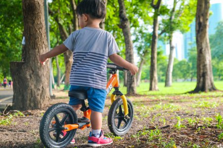 Photo for Preschool asian boy practice riding balansc bike in city park outdoor activity - Royalty Free Image