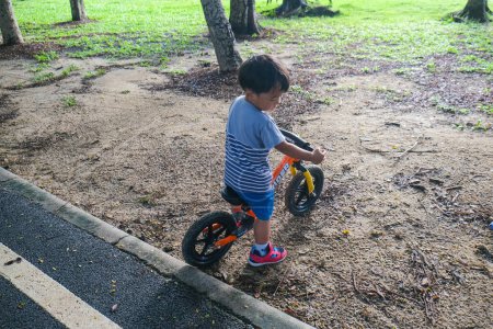 Photo for Preschool asian boy practice riding balansc bike in city park outdoor activity - Royalty Free Image