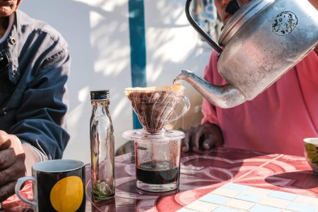 Foto de Hombre mano drrip elaboración de café local por papel filtrado en la mesa mañana al aire libre en casa - Imagen libre de derechos