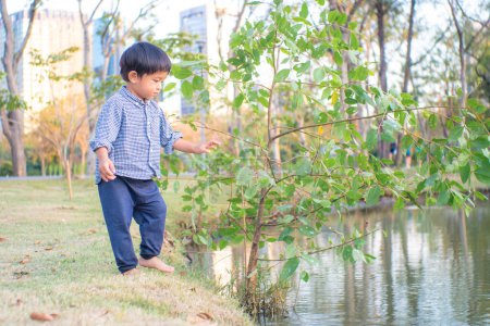 Photo for Toddler asian boy playing in city park river side outdoor recreation - Royalty Free Image
