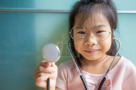Photo for Adorable glasses child girl playing with doctor costume with sthetoscope, Doctor kid - Royalty Free Image