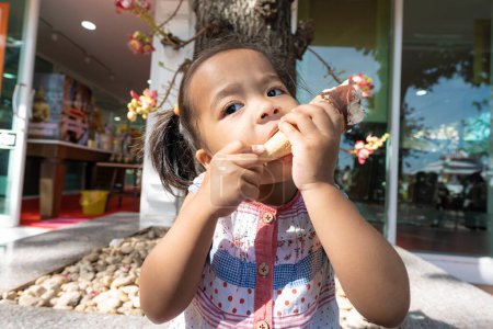 Téléchargez les photos : Heureux asiatique préscolaire fille appréciant manger icecream Voyage en été ville - en image libre de droit