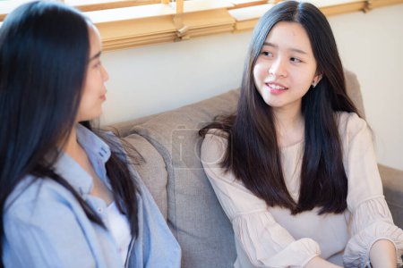 Téléchargez les photos : Heureux belle entreprise asiatique femme ami parler ensemble assis sur canapé assis dans maison bureau - en image libre de droit