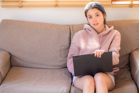 Téléchargez les photos : Business asiatique casual femme dactylographier sur ordinateur portable assis sur canapé dans confortable bureau à domicile technologie de l'information - en image libre de droit