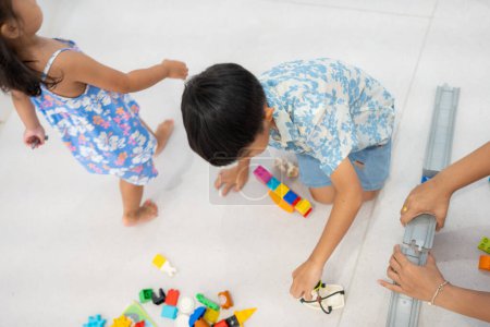 Foto de Adorable kindergarten niño asiático chico y chica disfrutando jugar colorido juguete bloque interior educación - Imagen libre de derechos