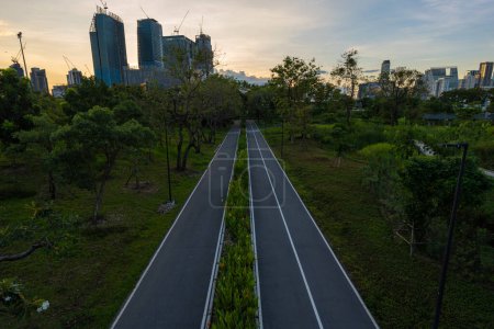 Téléchargez les photos : Chemin dans le parc forestier du centre-ville avec immeuble de bureaux Benchakitti Bangkok Thaïlande - en image libre de droit