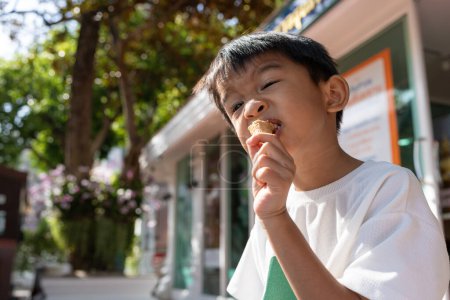 Photo for Asian boy kid hold scoops of strawberry and vanilla ice cream in waffles cone while summer vacation outdoor recreation - Royalty Free Image