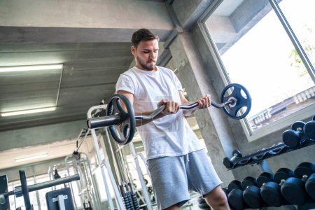 Téléchargez les photos : Sport homme levage haltère poids exercice salle de gym intérieure mode de vie sain - en image libre de droit