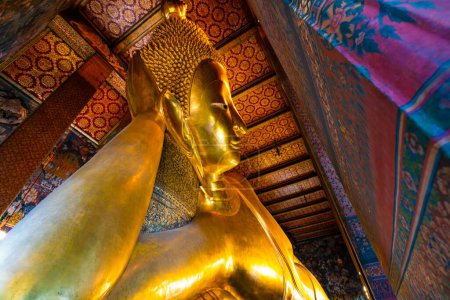 Foto de Estatua budista reclinable grande de oro en el templo que hace turismo en Bangkok Tailandia - Imagen libre de derechos
