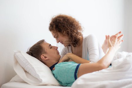 Téléchargez les photos : Couple d'amour couché sur un lit blanc le matin heureux et attentionné ensemble détente de l'amour - en image libre de droit