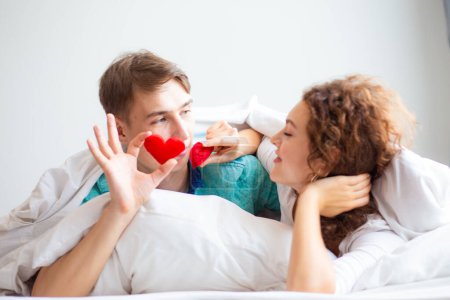 Foto de Amor pareja acostado en blanco cama manta celebrar corazón símbolo valentine concepto - Imagen libre de derechos