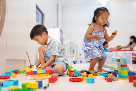 Foto de Adorable preescolar asiático chico y chica disfrutando jugar colorido edificio juguete bloque interior educación - Imagen libre de derechos