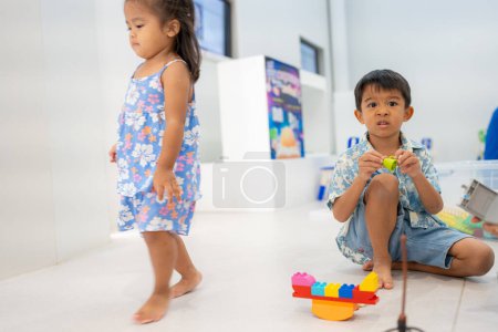 Foto de Adorable preescolar asiático chico y chica disfrutando jugar colorido edificio juguete bloque interior educación - Imagen libre de derechos