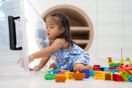 Foto de Linda niña asiática jugando con bloques de juguete coloridos en la guardería del jardín de infantes, niño pequeño en la guardería. - Imagen libre de derechos