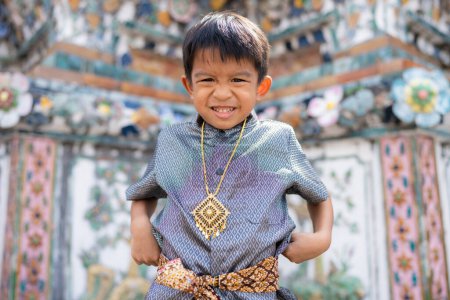 Foto de Pequeño chico asiático llevar traje tradicional tailandés viajar en el templo del amanecer Wat arun Bangkok Tailandia - Imagen libre de derechos