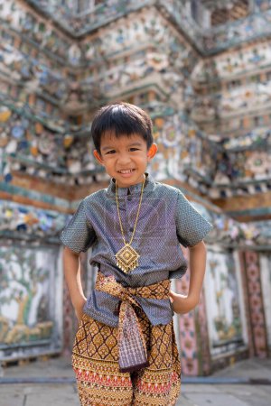 Foto de Little asiab boy wear traditional Thai suit travel in temple of dawn Wat arun Bangkok Thailand - Imagen libre de derechos
