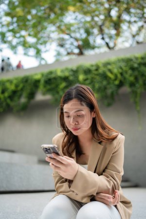 Téléchargez les photos : Business asiatique femme assis en plein air bureau café utiliser smartphone profiter connexion réseau social - en image libre de droit