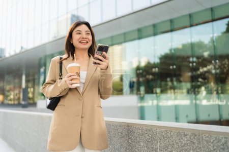 Foto de Inteligente negocio asiático mujer beber café uso smartphone en ciudad negocio oficina edificio al aire libre recreación negocio mujer - Imagen libre de derechos