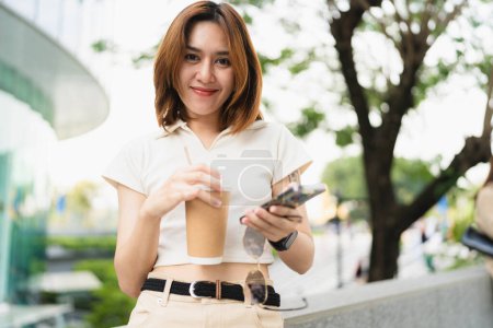 Téléchargez les photos : Smart business asiatique femme boire du café utiliser smartphone dans la ville bureau bâtiment loisirs en plein air femme d'affaires - en image libre de droit