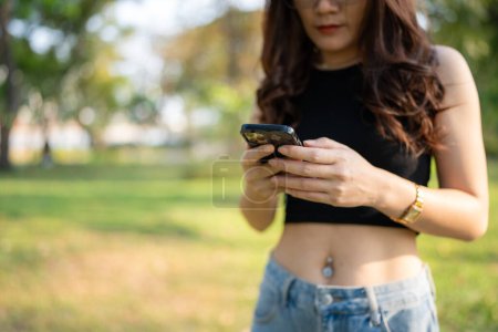 Business casual asiatique femme utiliser smartphone dans le parc de la ville coucher de soleil communication d'affaires en ligne