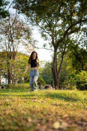 Téléchargez les photos : Portrait de femme asiatique se détendre dans le parc urbain coucher de soleil lumière ciel loisirs de plein air - en image libre de droit