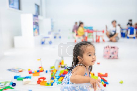 Foto de Linda niña asiática jugando con bloques de juguete coloridos en la guardería del jardín de infantes, niño pequeño en la guardería. - Imagen libre de derechos