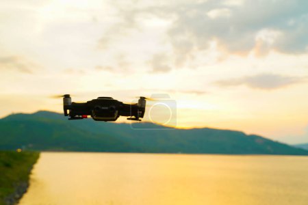 Photo for Silhouette drone flying over lake sunset colorful sky - Royalty Free Image