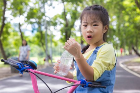 Foto de Asiático niño niña paseo bicicleta en árbol bosque ciudad público parque al aire libre ejercicio soleado día - Imagen libre de derechos