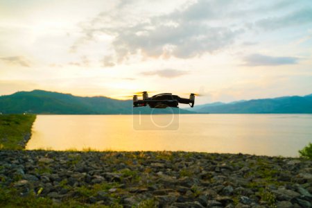 Foto de Silueta dron volando sobre el atardecer del lago cielo colorido - Imagen libre de derechos