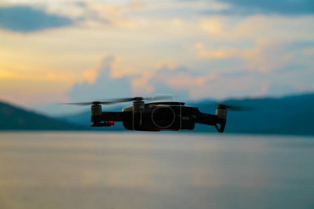 Téléchargez les photos : Silhouette drone volant au-dessus du lac coucher de soleil ciel coloré - en image libre de droit