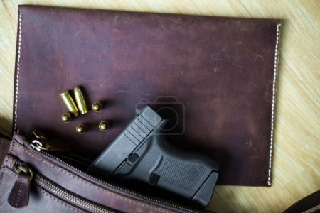 Téléchargez les photos : 9mm Sub compact everday porter pistolet moderne avec balle sur fond en cuir, pistolet de poche - en image libre de droit