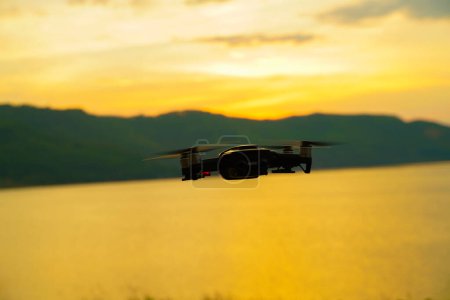 Téléchargez les photos : Silhouette drone volant au-dessus du lac coucher de soleil ciel coloré - en image libre de droit