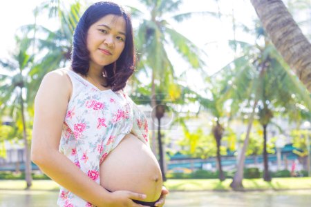 Téléchargez les photos : Asiatique jeune femme enceinte heureuse se détendre et profiter de la vie dans le parc naturel soleil ligfht espoir concept nouveau-né - en image libre de droit