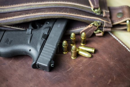 Téléchargez les photos : 9mm Sub compact everday porter pistolet moderne avec balle sur fond en cuir, pistolet de poche - en image libre de droit