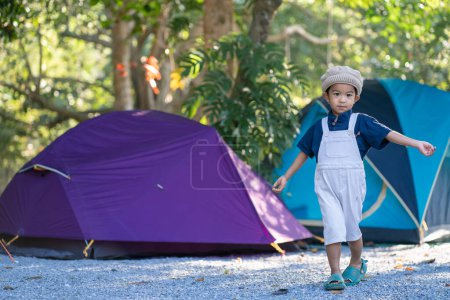 Happy kindergarten 5 year asian boy enjoying outdoor camping in rain forest camp site nature vacation