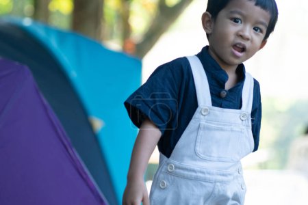 Happy kindergarten 5 year asian boy enjoying outdoor camping in rain forest camp site nature vacation