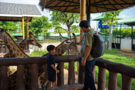 Photo for Asian father with adorable kindergarten kid boy and girl travel giraffe farm in zoo family travel - Royalty Free Image