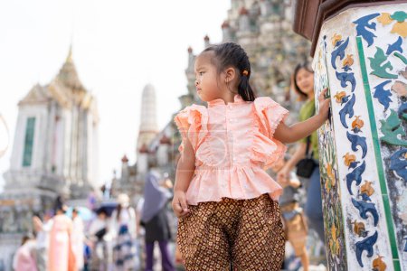 Foto de Niña del jardín de infantes usan traje de estilo tailandés viajan en Wat Arun buddhist templo turismo viajes en Bangkok Tailandia - Imagen libre de derechos