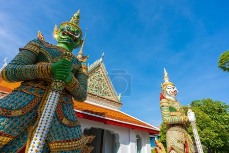 Téléchargez les photos : Statues de géants bouddhistes gardiens de démons aux portes de la salle d'ordination Wat Arun. Temple célèbre à Bangkok, Thaïlande. - en image libre de droit
