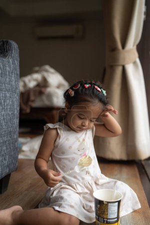 Téléchargez les photos : Adorable petite asiatique fille appréciant manger nouilles dans confortable maison - en image libre de droit