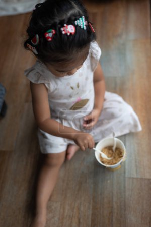 Téléchargez les photos : Adorable petite asiatique fille appréciant manger nouilles dans confortable maison - en image libre de droit