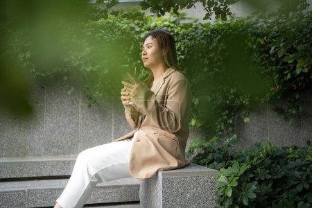Téléchargez les photos : Business asiatique femme boire du café à l'extérieur de la ville utilisation smartphone connexion Internet communication mobile - en image libre de droit