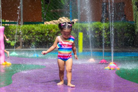 Photo for Adorable little girl enjoying in colorful city child water park outdoor activity summer vacation concept - Royalty Free Image