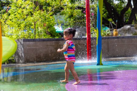Adorable little girl enjoying in colorful city child water park outdoor activity summer vacation concept