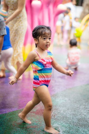 Photo for Beautiful adorable child girl enjoying play in outdoor water park in city child park - Royalty Free Image