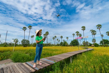 Téléchargez les photos : Asiatique entreprise agricultrice femme utiliser drone volant sur rizière smart agriculture technologie industrie agricole - en image libre de droit