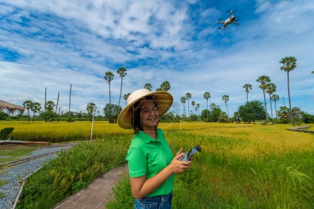Foto de Empresa asiática agricultora mujer uso dron volando sobre arroz campo inteligente agricultura tecnología agrícola industria - Imagen libre de derechos