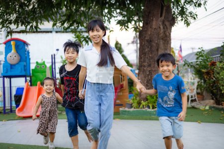 Téléchargez les photos : Petit asiatique garçon et fille enfants ami groupe courir ensemble dans enfant aire de jeux ville parc coucher de soleil lumière heureux temps - en image libre de droit