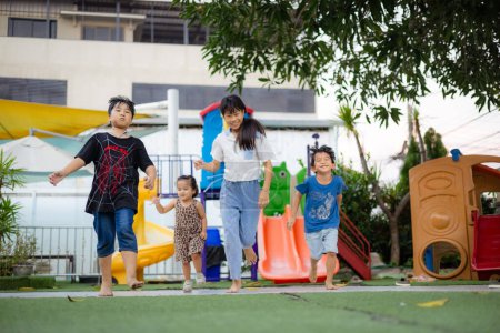 Foto de Poco asiático chico y chica niños amigo grupo corriendo juntos en niño parque de la ciudad parque puesta de sol luz feliz tiempo - Imagen libre de derechos